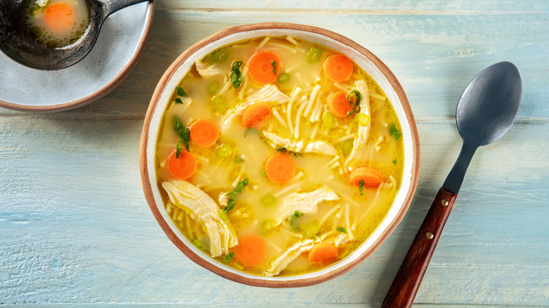 chicken noodle soup on table with spoon and ladle