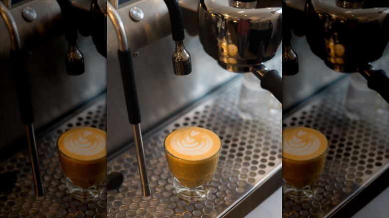 Latte just made with latte art, underneath a professional espresso machine at SK Coffee