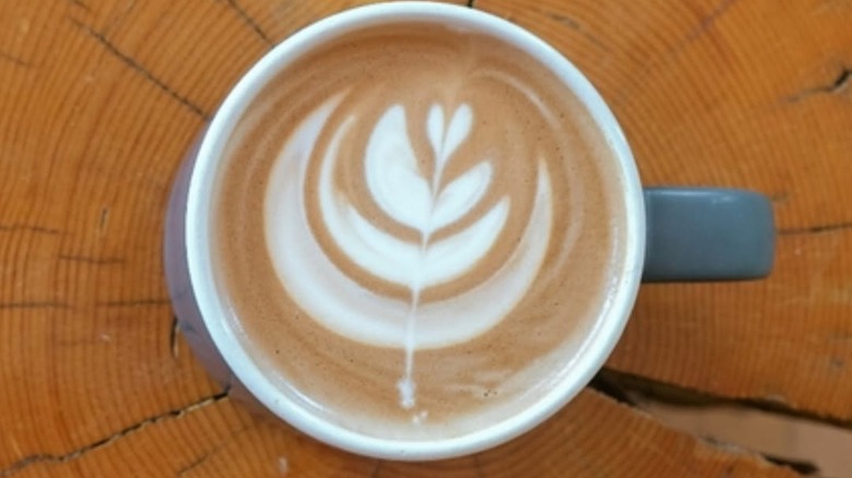 Latte with latte art placed on tree trunk table setup at Treeline Coffee Roasters