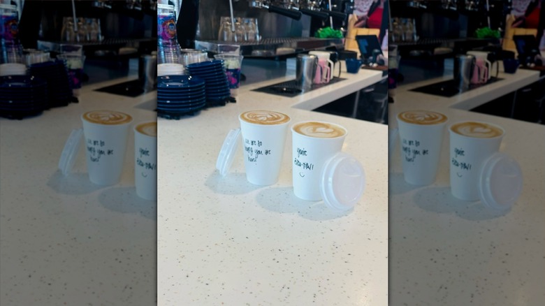 Two coffees side by side in white takeout cups