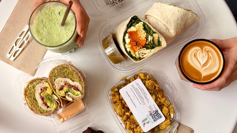 table view from above with an Iced Matcha, sandwhich wraps in to-go containers, and a latte from Sightsee