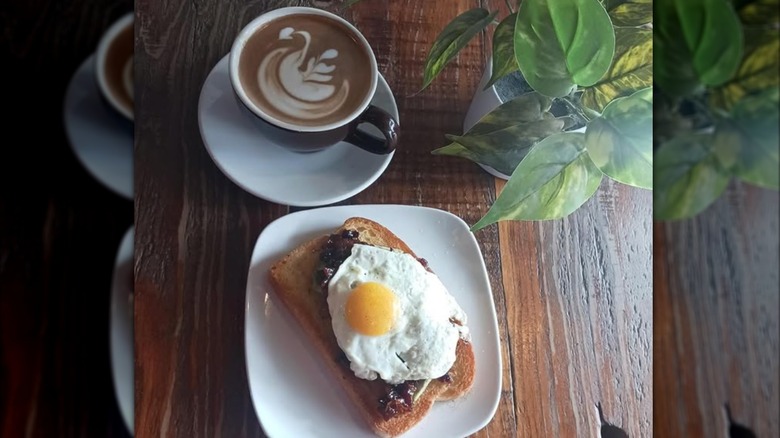 avocado toast with bacon jam topped with an egg, and a latte with latte art from Essence of Coffee