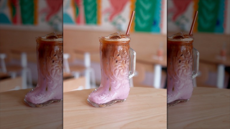 Super fun pink color iced coffee drink in a glass shaped like a cowboy boot from Matryoshka Coffee