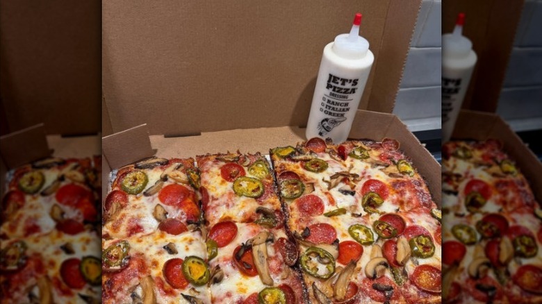 A box of Jet's Pizza with a squeeze bottle of ranch.