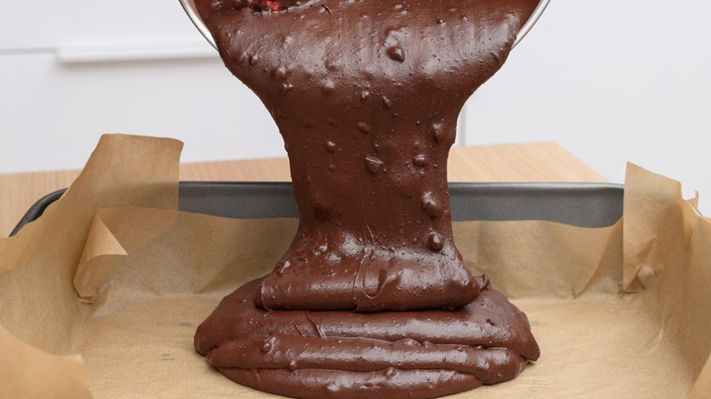 Chocolate cake dusted with powdered sugar on a wooden cake stand