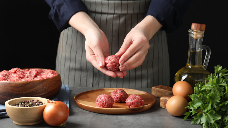 Woman rolling small ground beef meatballs