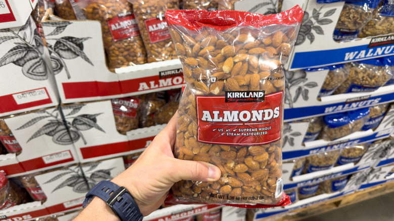 A person holds a bag of Kirkland Signature almonds