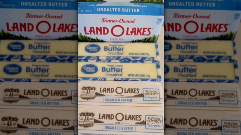 A box of Land O Lakes butter with four sticks of butter laid out in front, two are Great Value butter and two are Land O Lakes.
