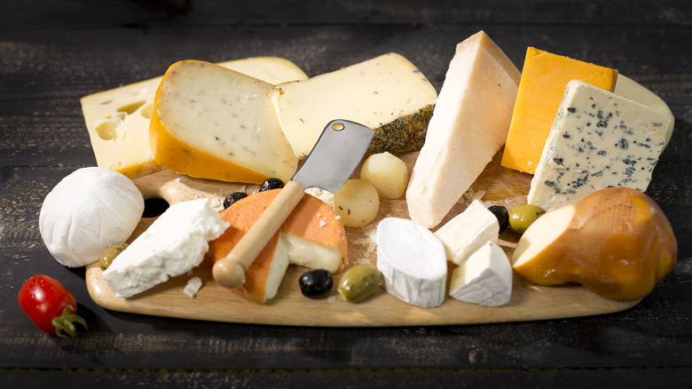 A variety of cheeses on a wooden cutting board