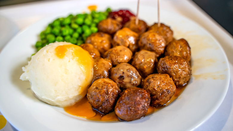 A white plate of IKEA meatballs, mashed potatoes, and peas