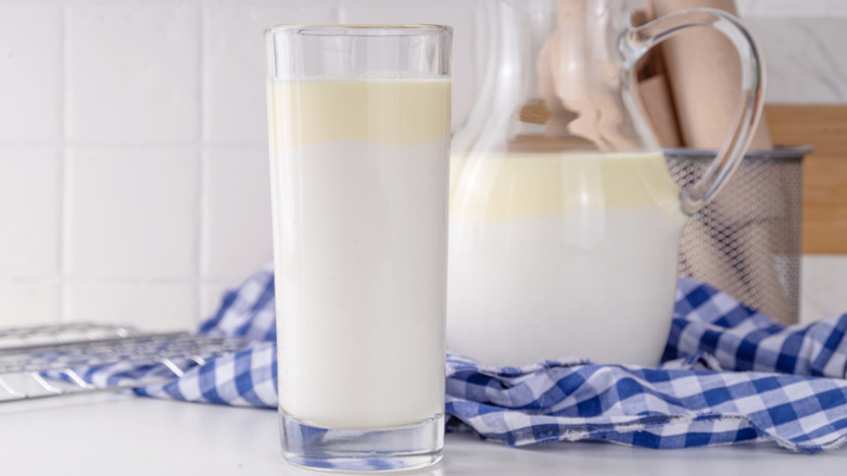 A glass and pitcher of cream-top, non-homogenized milk on a counter
