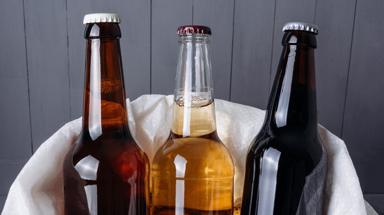 Three bottles of homebrewed beer in a bag of barley.