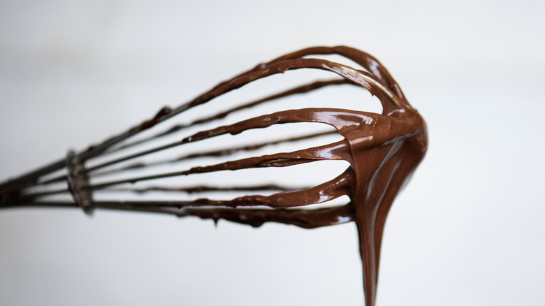 Chocolate ganache drips from a whisk