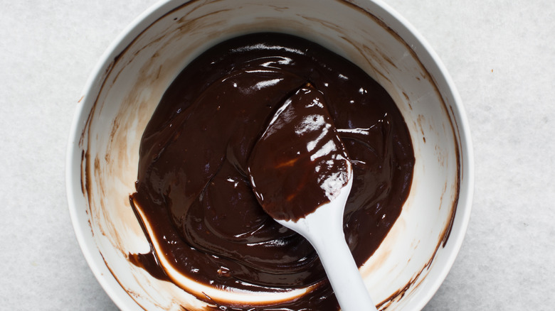 A bowl of chocolate ganache with a spatula