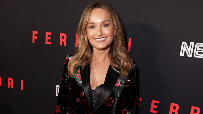 Close-up of Giada De Laurentiis wearing a black floral jacket in front of a black promotional background