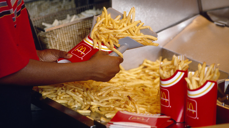 Workers putting McDonald's fries into red containers at restaurant fry station