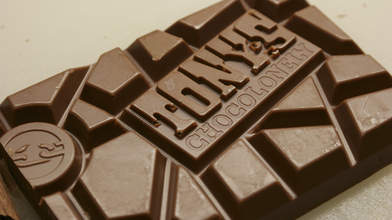 Close-up of the unequal parts of a Tony's Chocolonely bar on a beige surface