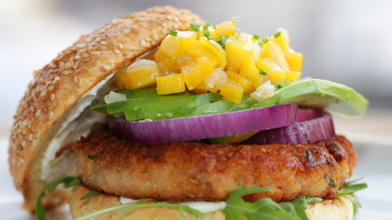 close up of shrimp burger with avocado, red onion, and mango salsa