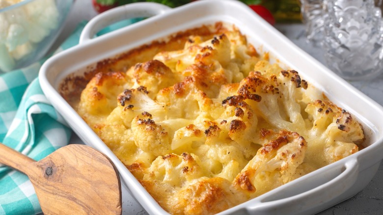 Cauliflower gratin in a casserole dish with a wooden serving spoon