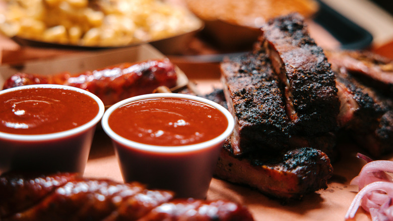 A platter of ribs, barbecue sauce, macaroni and cheese, and sausage from a barbecue restaurant