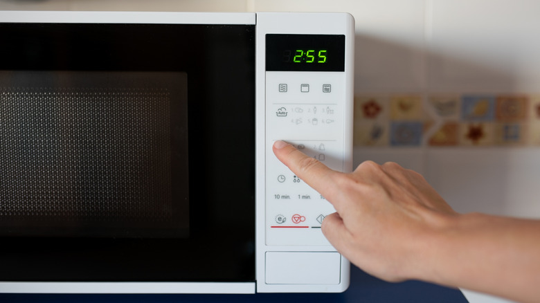 Pushing a button on a white microwave