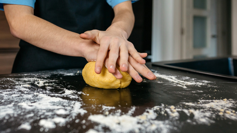 A person kneading fresh pasta dough