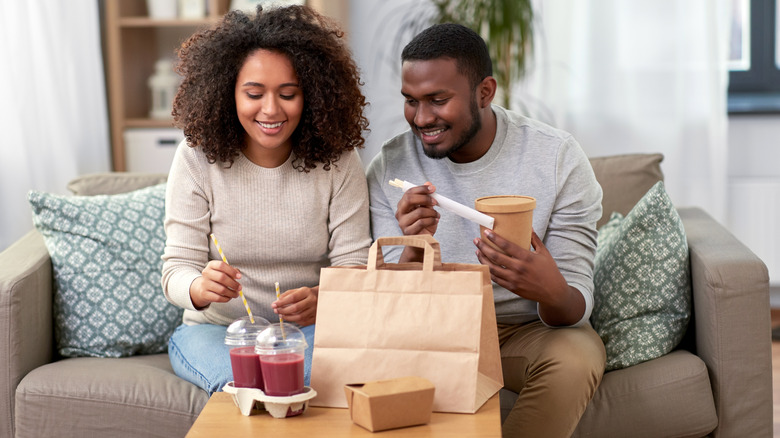 Couple with takeout food and drinks at home