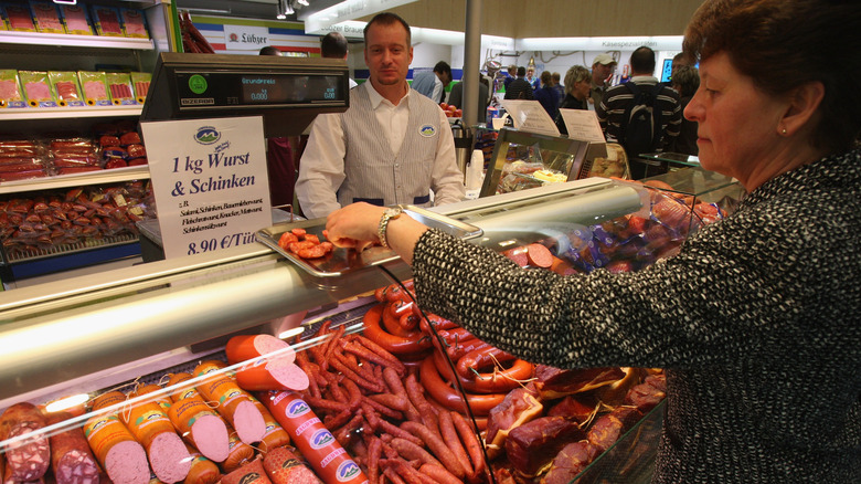 Woman weighing sausages at meat counter