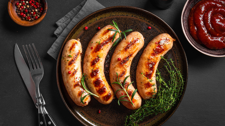 Browned sausages on a plate with place setting on a table