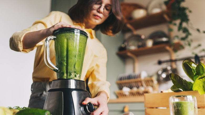Woman holding the lid while using a blender