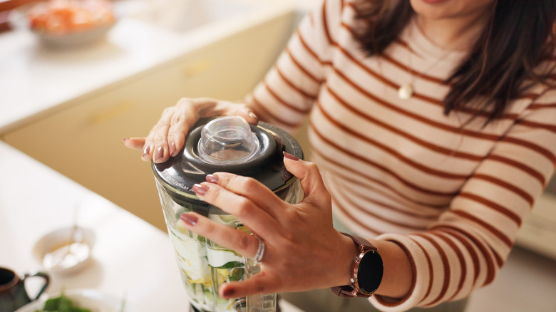 Woman holding down blender lid