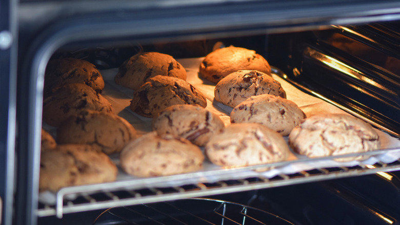 Cookies sit on parchment paper inside of an oven.