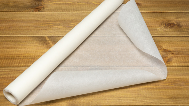 A partially unwrapped roll of parchment paper sits on a wooden background.