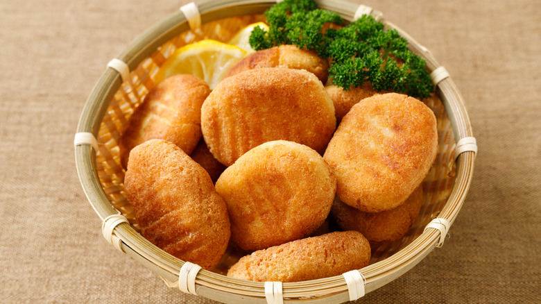 Wooden bowl of tofu nuggets with lemon and greens