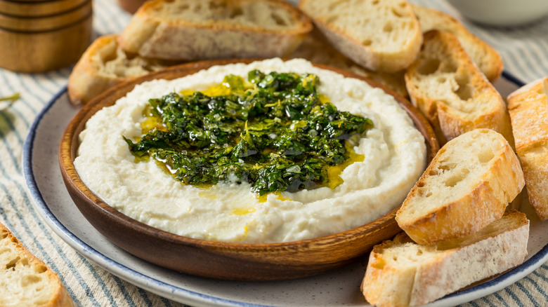 Whipped brie dip topped with olive oil and herbs served with toasted breads