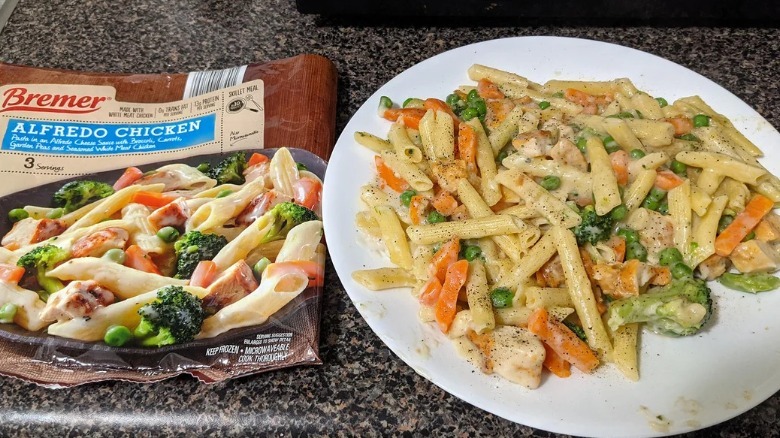 An empty bag of Bremer Alfredo Chicken Skillet Pasta alsongside a plate of the prepared pasta dish.