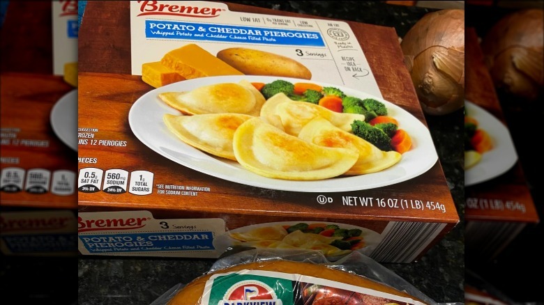 A box of Aldi's Bremer Potato & Cheddar Pierogies beside an onion.
