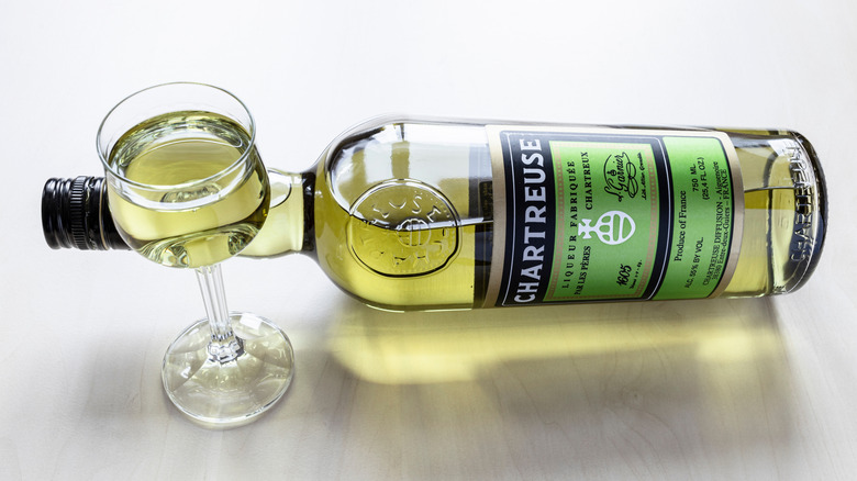 A bottle of Chartreuse on side with glass
