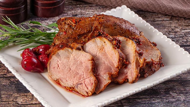 Sliced pork on square white plate on wood surface