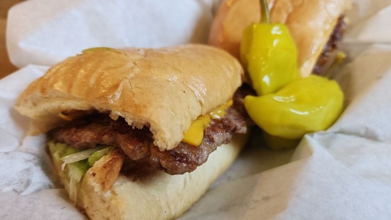 A Pass Key Italian sausage sandwich served on a crusty bun with cheese, lettuce, and banana peppers.