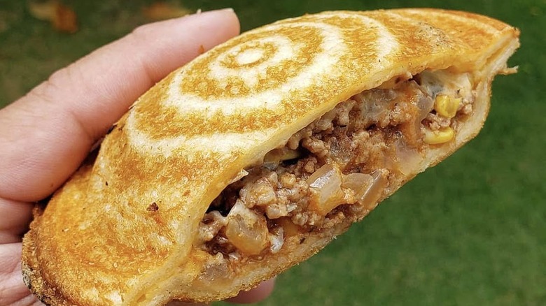 A Saucer King flying saucer sandwich, with iconic rings and filling of ground meat, sauce, onions, and corn.