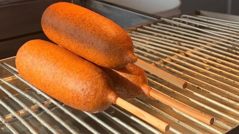 Three golden Pronto Pups stacked on a cooling rack.