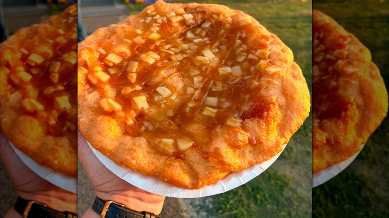 A plate-sized, crispy Elephant Ear topped with apple pie filling and sweet drizzle.