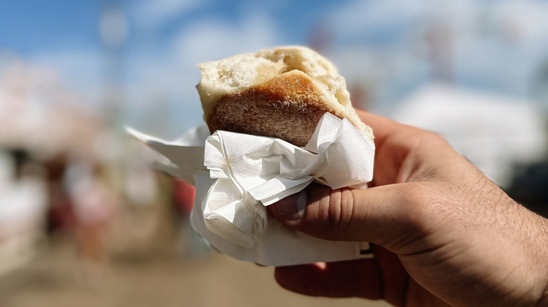 A hand holds a hot Biscuit Booth buttermilk biscuit wrapped in a napkin at the Mississippi State Fair.