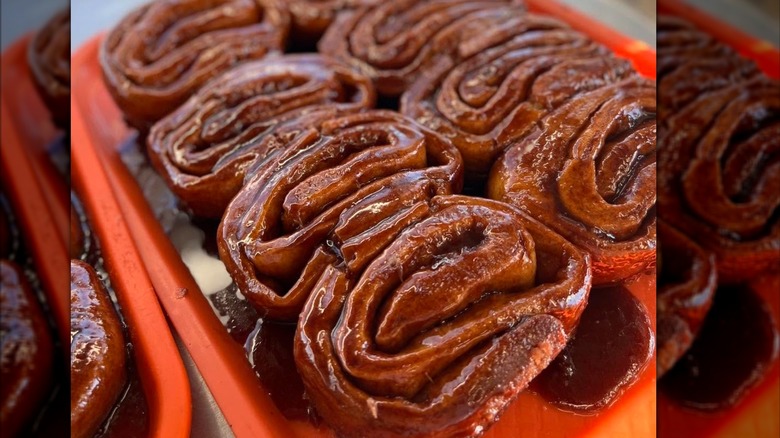 A tray of sweet rolls, glossy with cinnamon glaze.