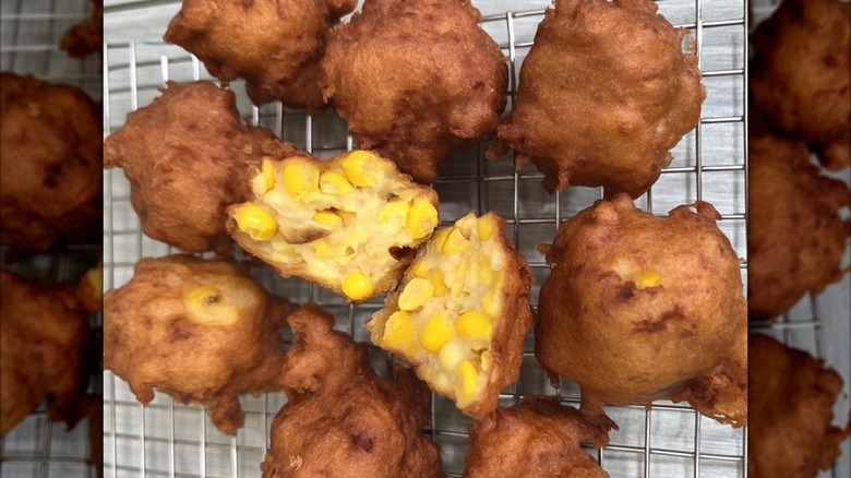 A cooling rack full of deep fried corn fritters.