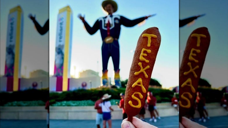 TEXAS spelled out in mustard on a Fletcher's Original Corny Dog held in the shadow of Big Tex at the State Fair of Texas.