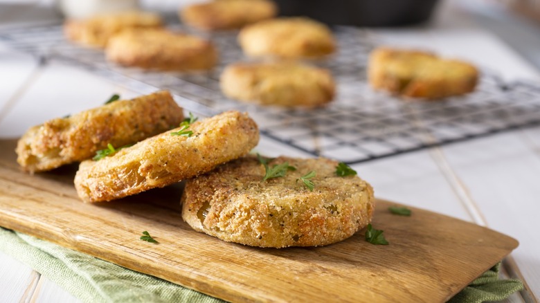 Fried green tomatoes resting on wooden cutting board