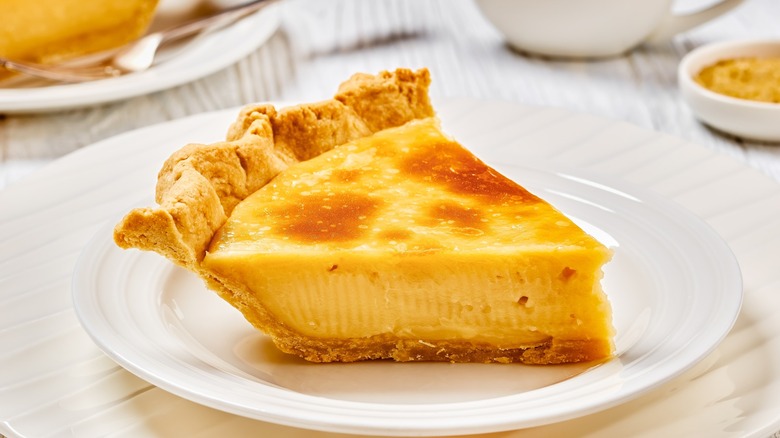 a slice of classic sugar cream pie, Hoosier pie, Indiana custard cream pie on white plate on white wood table