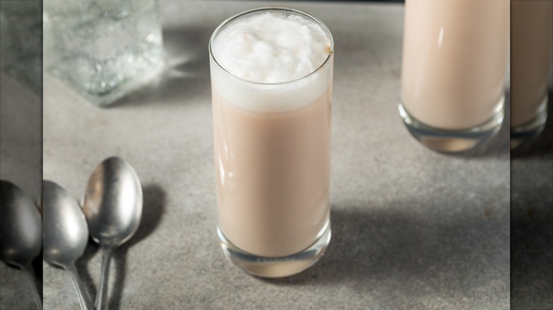 New York Egg Cream drink in a glass on a table with spoons beside it